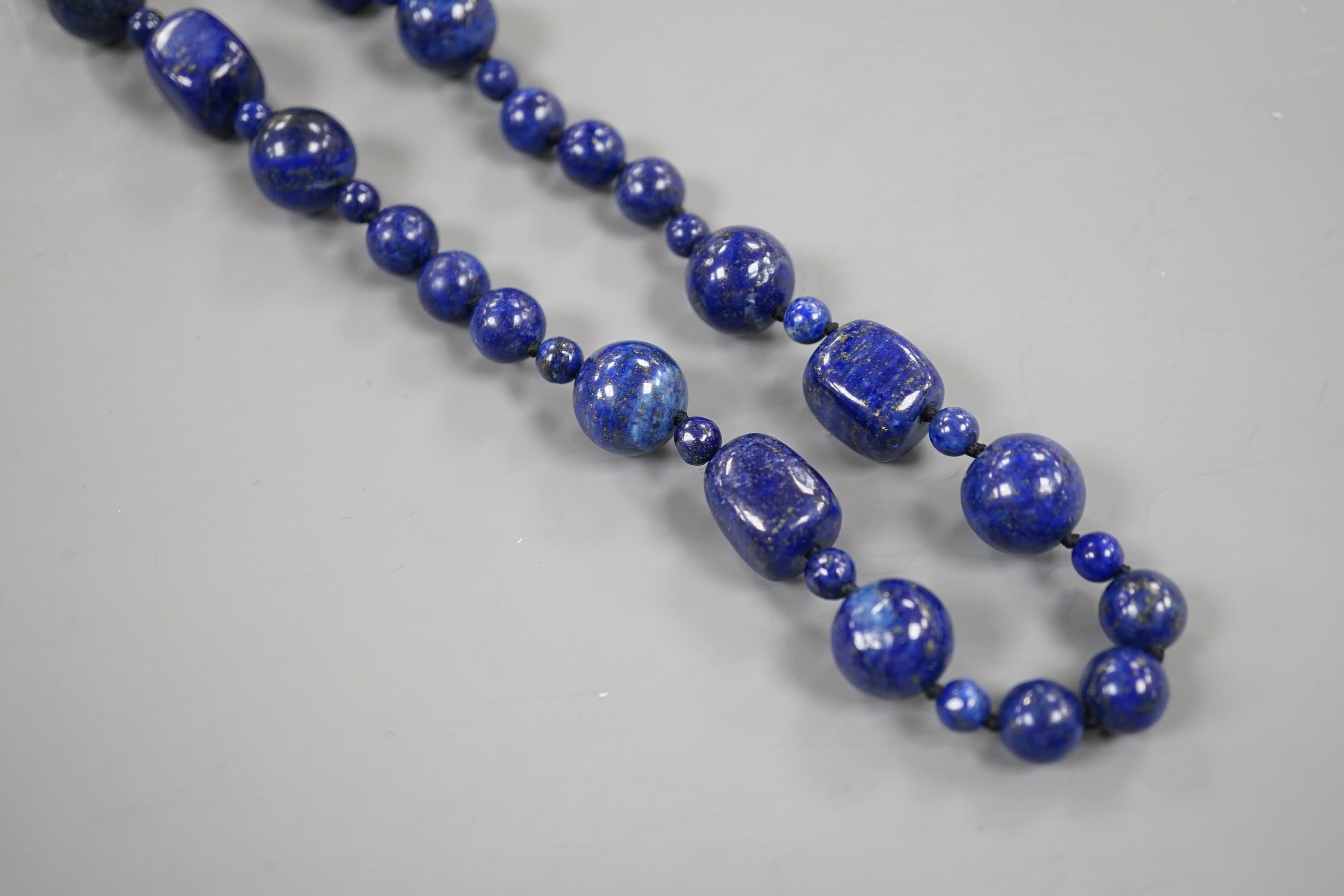A single strand lapis lazuli round and barrel bead necklace, 72cm.